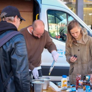 An einem Stand für Wohnungslose hantieren ein Mann und eine Frau